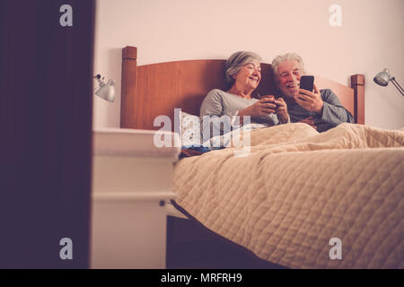 Schöne schöne Modelle Paar erwachsener Senior 70 Jahre alt Spaß und im Bett zu Hause im Schlafzimmer genießen. Morgens entspannt aufwachen mit No Rush e Stockfoto