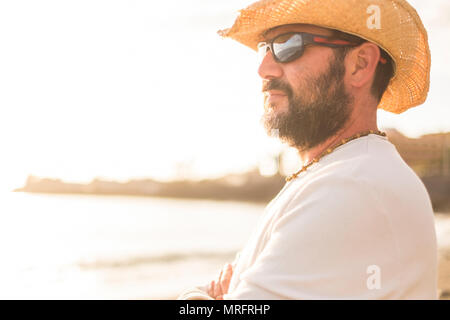 Mitte Alter 45 Jahre alten weißen Mann in Urlaub am Horizont mit einem golde Sonnenuntergang im Hintergrund. mit Sonnenbrille und Sommer Kleidung Stockfoto