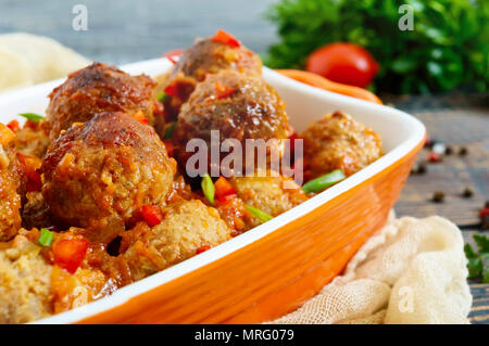 Saftige Fleischklößchen in pikanter Tomatensauce auf einem Holztisch. Gericht aus Hackfleisch. Stockfoto