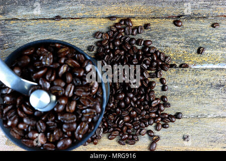 Geröstete Kaffeebohnen in einer kaffeemühle von Hand. Und Fokus auf gerösteten Kaffeebohnen auf einer hölzernen Hintergrund verbreiten. Stockfoto