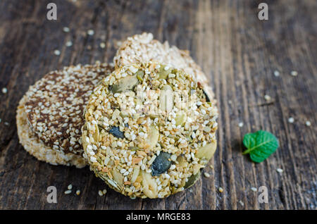 Dessert Müsli Snacks. Fitness diätetische Lebensmittel. Kozinaki mit Sesam, Erdnuss-, Sonnenblumen- und Kürbiskernen und Chocolate Chip auf alten rustikalen Holzbrett, Stockfoto