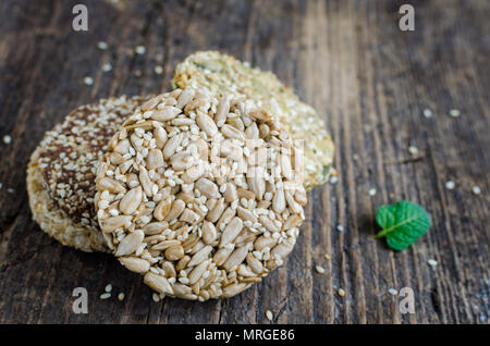 Dessert Müsli Snacks. Fitness diätetische Lebensmittel. Kozinaki mit Sesam, Erdnuss-, Sonnenblumen- und Kürbiskernen und Chocolate Chip auf alten rustikalen Holzbrett, Stockfoto