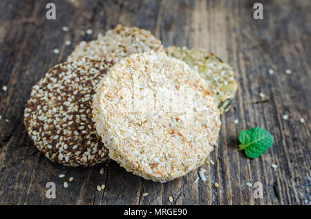 Dessert Müsli Snacks. Fitness diätetische Lebensmittel. Kozinaki mit Sesam, Erdnuss-, Sonnenblumen- und Kürbiskerne, Schokolade und Kokos auf alten rustikalen Holzmöbeln bo Stockfoto