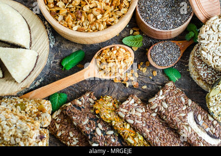 Gesunde Snacks. Diätetische Lebensmittel. Sesam Halva. Flocken, Chia Samen in zwei Schüsseln und Löffel. Kozinaki, drei Energieriegel und Minze. Die Grissini mit fla Stockfoto