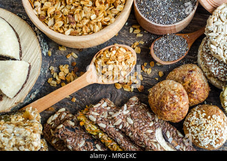 Gesunde Snacks. Diätetische Lebensmittel. Sesam Halva. Flocken, Chia Samen in zwei Schüsseln und Löffel. Kozinaki, drei Müsliriegel. Die Grissini mit Flachs, sunfl Stockfoto