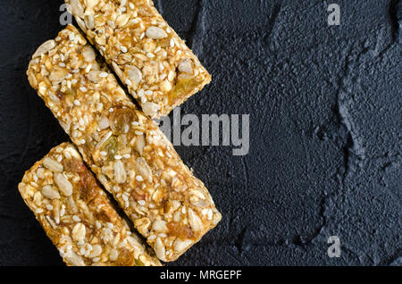 Gesunden Snack. Fitness diätetische Lebensmittel. Drei selbstgemachte Granola Bars mit Haferflocken, Sesam, Sonnenblumen- und Kürbiskerne, Rosinen, Honig auf der Schiefer pla Stockfoto