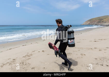 Ein Scuba diver Spaziergänge in Richtung Ozean und für einen Strand Tauchen (shore Dive) an einem sonnigen Tag in Malibu, Kalifornien. Stockfoto