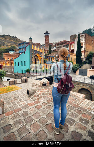 Touristische Frau in braunen Sakko unter Bild der öffentlichen Schwefelsäure Badewanne von Ihrem Smartphone in Tiflis, Georgien Stockfoto