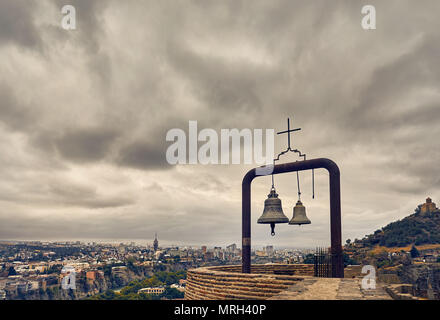 Alte mittelalterliche Festung Narikala mit großen Glocken an der Wand bedeckt bewölkten Himmel in Tiflis, Georgien Stockfoto