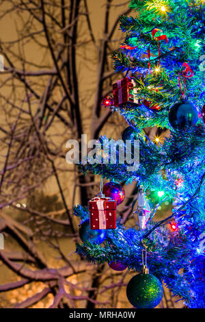 Weihnachtsschmuck auf einem Zweig der Fir, Nacht Idylle, mit Schnee und Lampen in verschiedenen Farben Stockfoto