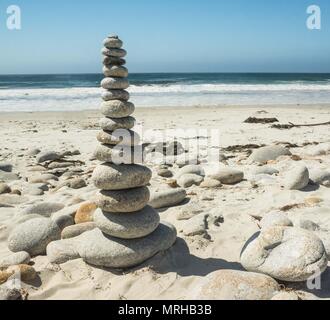 Gestapelte Steine auf einen Sandstrand am Meer. Stockfoto