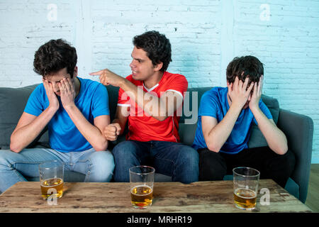 Junge Gruppe der kaukasischen Fußball-Fans enttäuscht und glücklich gerade ein Fußballspiel auf der Couch. Stockfoto