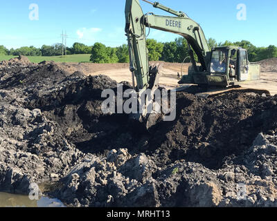 Ein U.S. Army Reserve horizontale Bau Ingenieur vom 411. Engineer Company, 416th Theater Ingenieur Befehl, betreibt ein Bagger an Boden, dass mit Wasser aufgrund der jüngsten Niederschläge in Montrose, Minnesota, 15. Juni 2017 gesättigt ist, dig. Trotz unvorhergesehenen Missgeschick aus dem Wetter, Soldaten der 411. Ingenieur Unternehmen sind in der Lage und bereit, die Transformation der in diesem Feld in das Fundament für eine Sportanlage als Teil der innovativen Readiness Training zu absolvieren. (U.S. Armee finden Foto von Kapitän Michael Havro 211 Mobile Public Affairs Abteilung) Stockfoto