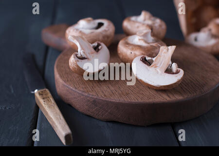 Pilze Champignons in eine Papiertüte, auf einem Holzbrett und Messer. im Hintergrund. Platz kopieren Stockfoto