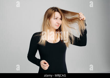 Pretty Woman Holding unordentlichen Haar in einer Hand und Haarbürste in ein anderes. Stockfoto