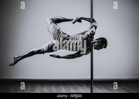 Junge starke Mann Pole Dancing. Schwarze und weiße dramatische Farben. Stockfoto