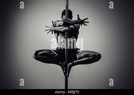 Junge starke Mann Pole Dancing. Schwarze und weiße dramatische Farben. Stockfoto