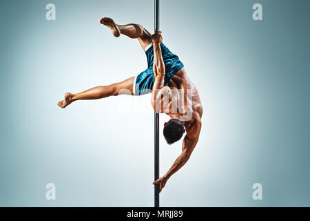 Junge starke Mann Pole Dancing auf blauem und weißem Hintergrund Stockfoto
