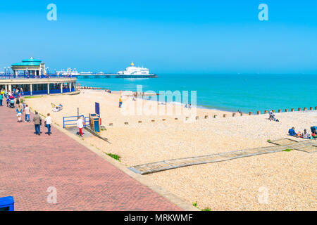 EASTBOURNE, Sussex, UK - Mai 20,2018: Menschen am Strand entspannen in Eastbourne, einem Badeort in East Sussex. Die Küste ist mit viktorianischen Uhr gefüttert Stockfoto