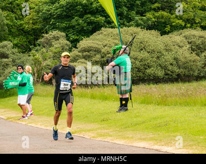 Edinburgh Marathon Festival, 26. Mai 2018. Gosford Estate, East Lothian, Schottland, Großbritannien. Marathonläufer an der Meile 18 Daumen hoch geben Geste mit Macmillan Cancer Charity stehen und Mann im Kilt Dudelsack spielen Stockfoto