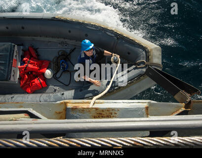 Arabischen Golf (20. Juni 2017) Engineman 3. Klasse Joshua Hohn, zugeordnet zu den Coastal Patrol Schiff USS Feuerblitz (PC 10), arbeitet eine Linie auf einem starren - Rumpf Schlauchboot zu sichern, da es neben der geführten - zieht missile Cruiser USS Vella Golf (CG 72 für Personal transfer während der Übung Spartan Kopis 17. Übung Spartan Kopis ist eine Task Force (TF) 55 - LED-Übung zwischen der US Navy und der US-Küstenwache, um taktische Kenntnisse verbessern, erweitern und Ebenen der Zusammenarbeit, gegenseitige Unterstützung und langfristige Sicherheit und Stabilität in der Region erhöhen. Vella Golf ist in die US bereitgestellt Stockfoto