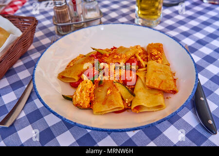 Paccheri Pasta mit Zucchini Red Cherry Tomaten und Riccota Käse - Traditionelle italienische Dishe serviert auf einem traditionellen gedeckten Tisch Stockfoto
