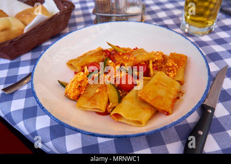 Paccheri Pasta mit Zucchini Red Cherry Tomaten und Riccota Käse - Traditionelle italienische Dishe serviert auf einem traditionellen gedeckten Tisch Stockfoto