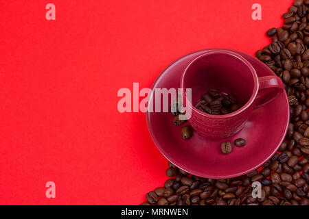 Leere Tasse Kaffee und Kaffeebohnen auf rotem Hintergrund Stockfoto