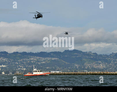 Besatzungsmitglieder an Bord des California Air National Guard 129 Rettung Flügel HH-60G Pave Hawk Hubschrauber fliegen über ein Coast Guard Station San Francisco 45-Fuß-Antwort Boot - Mittel bei einer gemeinsamen Übung in der Bucht von San Francisco, den 25. April 2017. Mitglieder aus der Sicherheit und Gefahrenabwehr im Seeverkehr Team 91109, in San Diego, durchgeführt fast-rope Übungen aus dem HH-60G Pave Hawk Hubschrauber während eines interagency Training. U.S. Coast Guard Foto von Petty Officer 2. Klasse Matthew S. Masaschi. Stockfoto