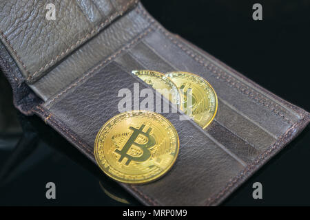 Gold bitcoins aus braunem Leder Brieftasche auf schwarzem Hintergrund Stockfoto