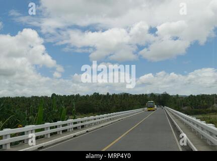 Tagum, Davao del Norte, März 2016: Fahrzeuge fahren über eine lange Brücke über einen Fluss und Bananenplantagen in Tagum, Davao del Norte, Philippinen Stockfoto