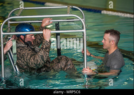 (Von links) Kapitän David Shadoin, 54 Helicopter Squadron Pilot, ist unterrichtet, die die Tech. Sgt. Clifton Cleveland, 5 Operations Support Squadron überleben, Steuerhinterziehung, Widerstand und Flucht Spezialist, während underwater Survival Training in Minot Air Force Base, N.D., 22. Juni 2017. Das seichte Wasser egress Trainer ermöglicht Flieger escape Verfahren während eines simulierten Absturz eines Hubschraubers zu üben. (U.S. Air Force Foto von Airman 1st Class Jonathan McElderry) Stockfoto