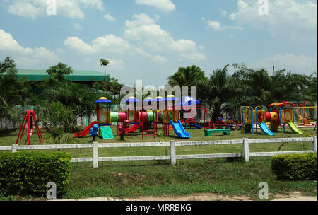 Kinderspielplatz mit Rutschen, Leitern, Klettergerüste, Klettern - über Lokomotive und mechanische rockigen Fahrten, Udon Thani, Isaan, Thailand Stockfoto