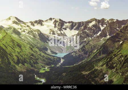 Top view River im Frühling. Der Fluss umgibt, bunten Feld. Berge Hänge sind mit üppigen grünen Vegetation bedeckt. Stockfoto