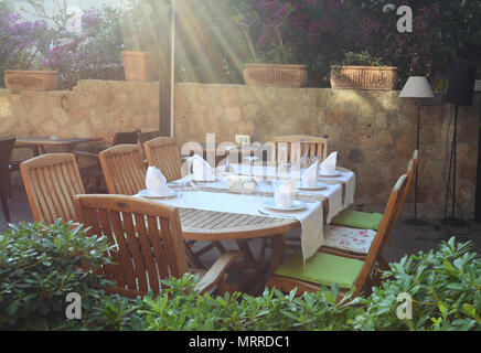 Serviert Tisch für fünf Personen in die Sommerterrasse des Restaurants in den Strahlen der Abendsonne Stockfoto