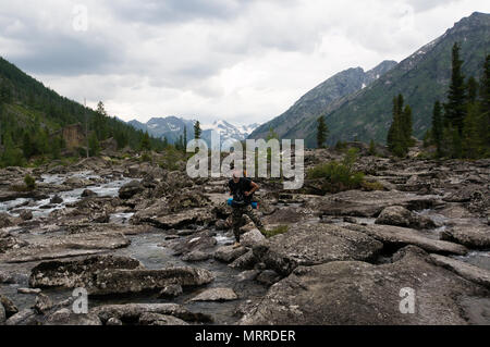 Wanderer ascenting in einem Berge. Touristen mit einem großen Rucksack am Abend durch den Stein schleichen Ablagerungen auf der Bergseite. Stockfoto