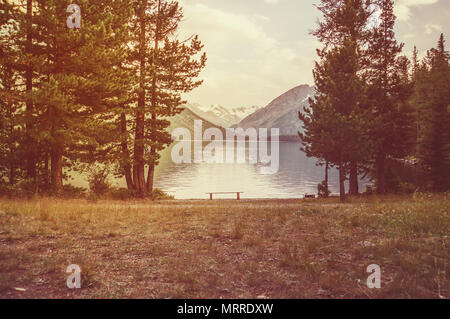 See Berglandschaft und Holzbank. leeren Bank in der Natur. Stockfoto