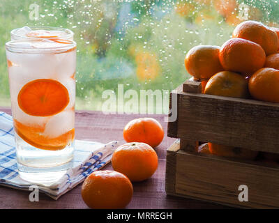Ein Glas detox mit Mandarine und Eis, neben einer Box von Mandarinen, Detox, Frühstück und gesunden Lebensstil Konzept. Stockfoto
