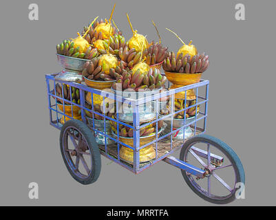 Trolley enthält Rohstoffe Bananen und golden Kokosnüsse in silbernen und goldenen Fächer für Religiöse, auf isolierte grauer Hintergrund mit Freistellungspfaden. Stockfoto