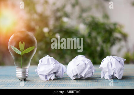 Speichern Sie die Welt Konzept, kleiner Baum wachsen oben in Lampe mit Recycling Papier auf Tisch Stockfoto