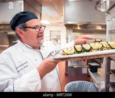 Maynard Oestreich, Executive Chef für Aramark Mahlzeiten bereitet vor der Flieger Führung Schulabschluss bei Travis Air Force Base, Calif., 28. Juni 2017. Oestreich einem ehemaligen US Navy Veteran und einem preisgekrönten Küchenchef aus Napa Valley, Calif., nahm der Küchenchef Position, so dass er Mentor junger Flieger könnte. (U.S. Air Force Foto von Louis Briscese) Stockfoto