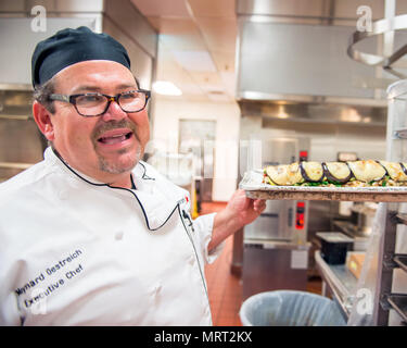 Maynard Oestreich, Executive Chef für Aramark Mahlzeiten bereitet vor der Flieger Führung Schulabschluss bei Travis Air Force Base, Calif., 28. Juni 2017. Oestreich einem ehemaligen US Navy Veteran und einem preisgekrönten Küchenchef aus Napa Valley, Calif., nahm der Küchenchef Position, so dass er Mentor junger Flieger könnte. (U.S. Air Force Foto von Louis Briscese) Stockfoto