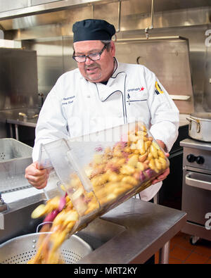 Maynard Oestreich, Executive Chef für Aramark Mahlzeiten bereitet vor der Flieger Führung Schulabschluss bei Travis Air Force Base, Calif., 28. Juni 2017. Oestreich einem ehemaligen US Navy Veteran und einem preisgekrönten Küchenchef aus Napa Valley, Calif., nahm der Küchenchef Position, so dass er Mentor junger Flieger könnte. (U.S. Air Force Foto von Louis Briscese) Stockfoto