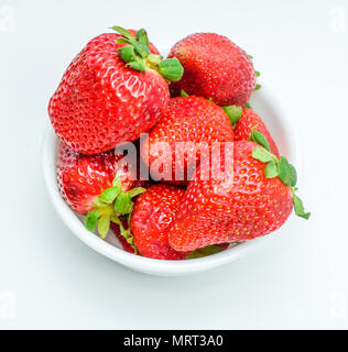 Frische reife Erdbeeren mit Blättern in einer Schüssel auf weißem Hintergrund Stockfoto