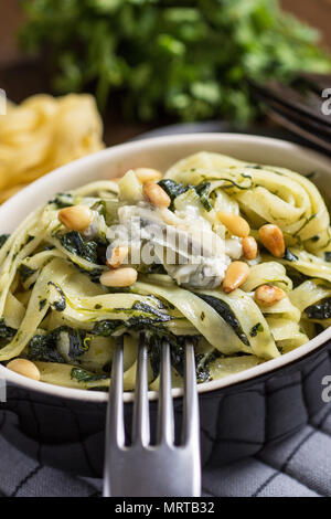 Frisch zubereitete Tagliatelle mit Blattspinat, Pinienkernen und Gorgonzola Stockfoto