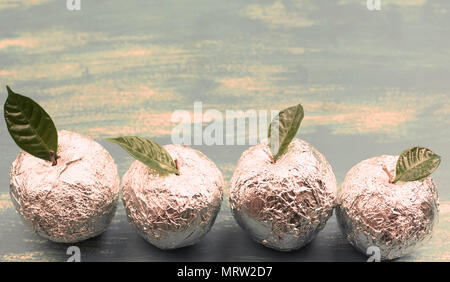 Banner vier Äpfel in Folie eingewickelt sind natürliche grüne Blätter. Holz- candy blauen Hintergrund. Flach Top View Stockfoto