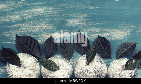 Banner vier Äpfel in Folie eingewickelt sind natürliche grüne Blätter. Holz- candy blauen Hintergrund. Flach Top View Stockfoto