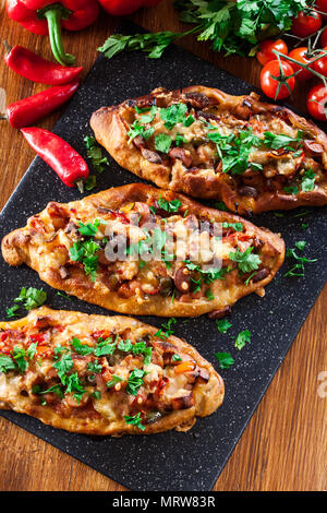 Traditionelle türkische Pide mit Fleisch und Gemüse auf Schneidebrett. Ansicht von oben Stockfoto