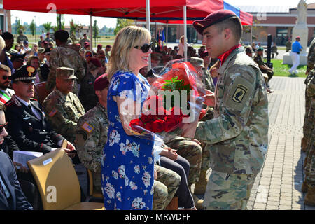 Ehefrau von Oberst Gregory Anderson, ausgehende Kommandant der 173Rd Airborne Brigade, erhält ein Bouquet von roten Blumen aus ein Fallschirmjäger bei der Änderung von Befehl Zeremonie an Caserma Del Din in Vicenza, Italien, 7. Juli 2017. Die 173Rd Airborne Brigade, in Vicenza, Italien, ist die Armee Contingency Response Force in Europa, und ist in der Lage, Kräfte projizieren, das volle Spektrum militärischer Operationen in den Vereinigten Staaten der Europäischen, Zentralen und Verantwortungsbereiche afrikanischen Befehle durchzuführen. (U.S. Armee Foto von visuellen Informationen Spezialist graigg faggionato/Freigegeben) Stockfoto