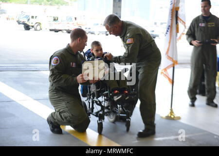 Coast Guard Kapitän Mark Morin und Petty Officer 1st Class Keola Marfil anwesenden ehrenamtlichen Petty Officer 3rd Class Andrew Bischof eine Medaille bei Coast Guard Air Station Kodiak, Alaska, 8. Juli 2017. Bischof erhielt die Auszeichnung beim Besuch der Air Station seinen Wunsch erfüllen, ein Coast Guard Rettungsschwimmerin in Alaska. U.S. Coast Guard Foto von Petty Officer 2nd class Meredith Manning Stockfoto